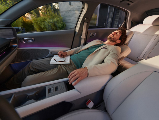 man with white suit and green t-shirt is laying on the 8-way adjustable seat of the Hyundai IONIQ 6